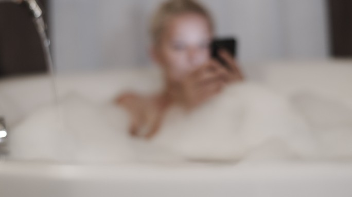 斯洛·莫（SLO MO）在泡泡浴时使用手机
