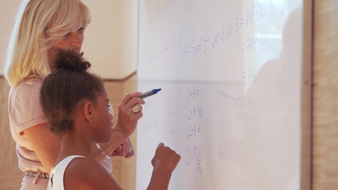 聪明的女小学生和老师在白板上做数学