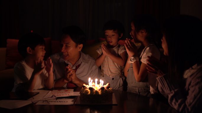 一个温暖的家庭坐在一起吹爸爸的生日蛋糕每个人都很高兴能在一起。它代表着爱和纽带，作为一个温暖的家庭团