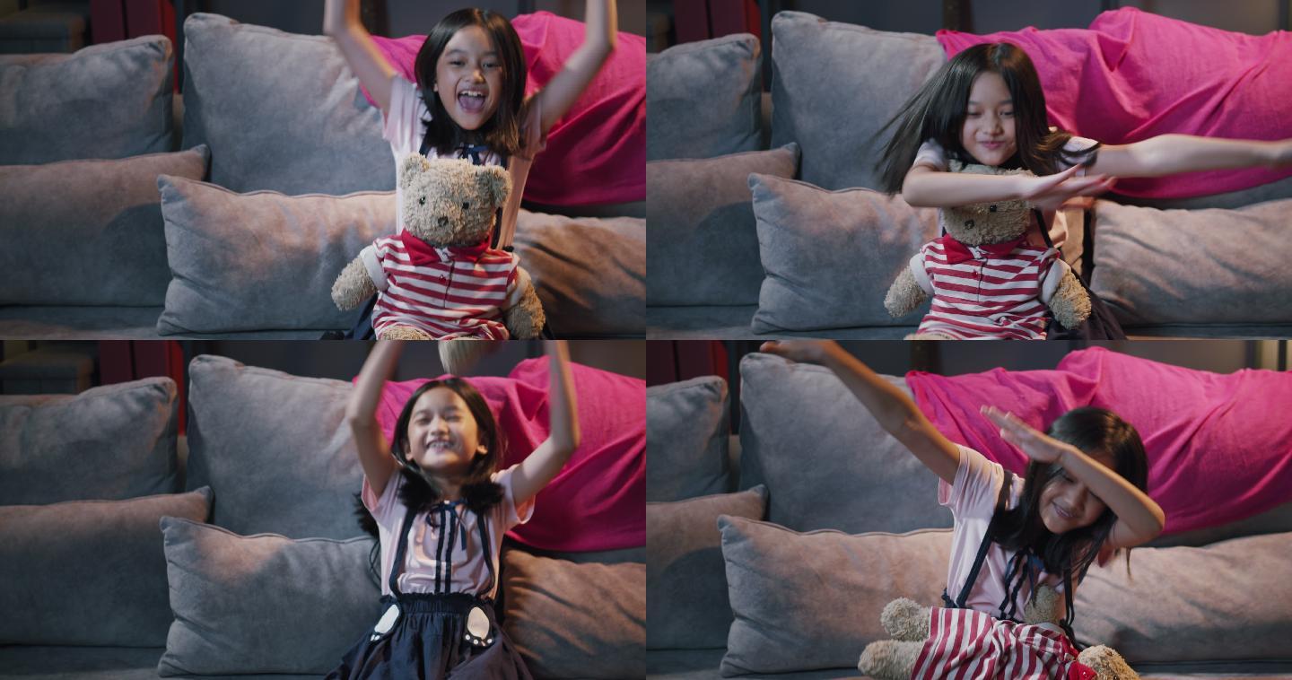 可爱的女孩和可爱的泰迪熊娃娃在电视上看滑稽电影。