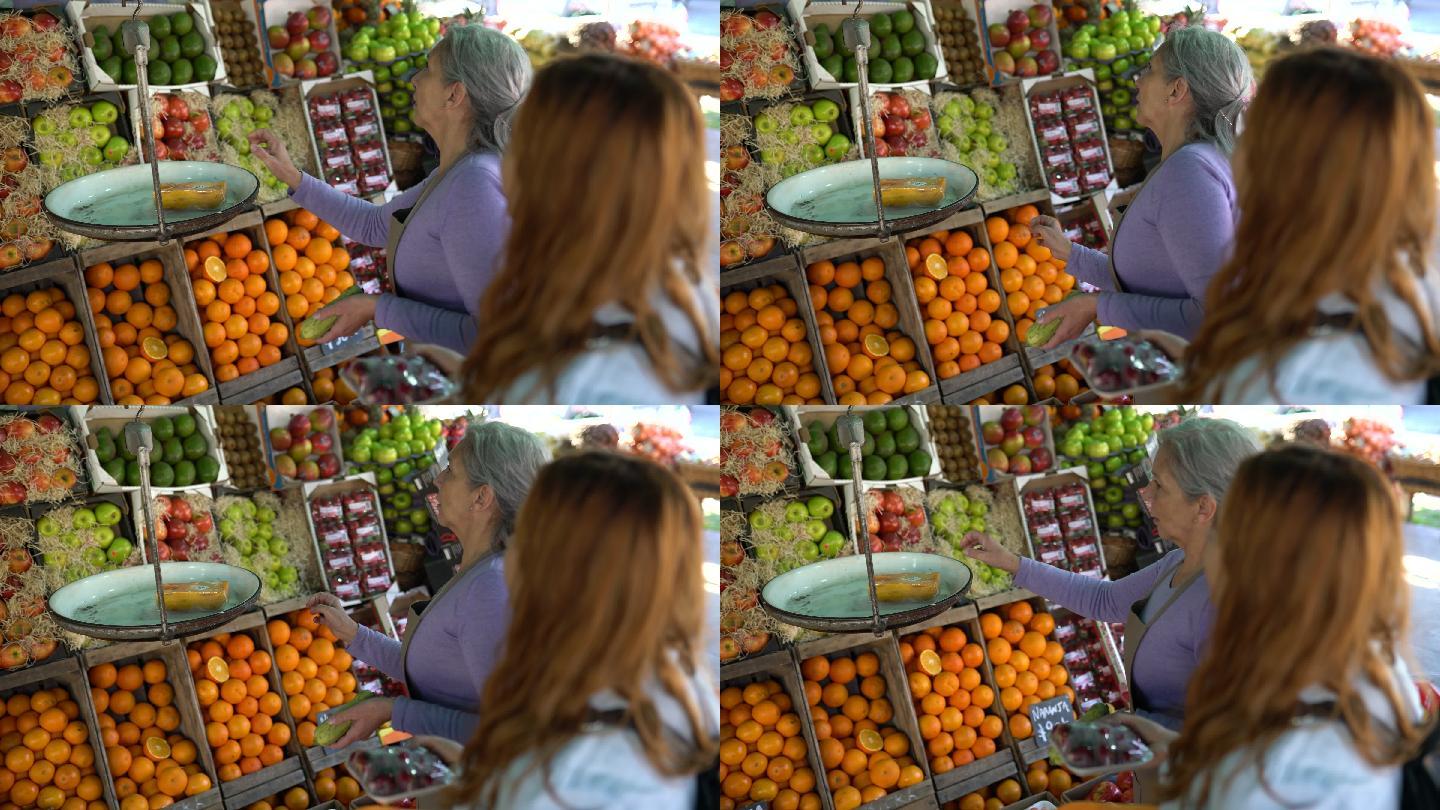 拉丁美洲一位老妇人为在农贸市场购物的年轻顾客称量蔬菜重量