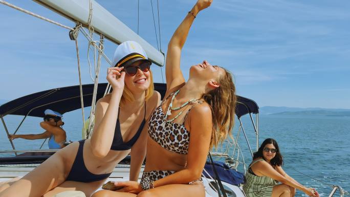 阳光明媚的日子里，两位女性朋友在游艇上晒日光浴时合影留念