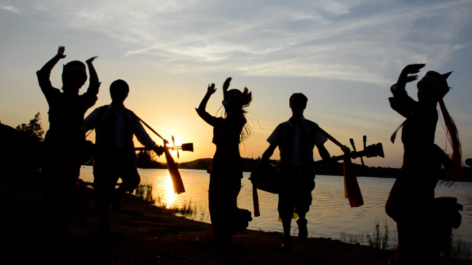 夕阳下湖水边少数民族舞蹈剪影