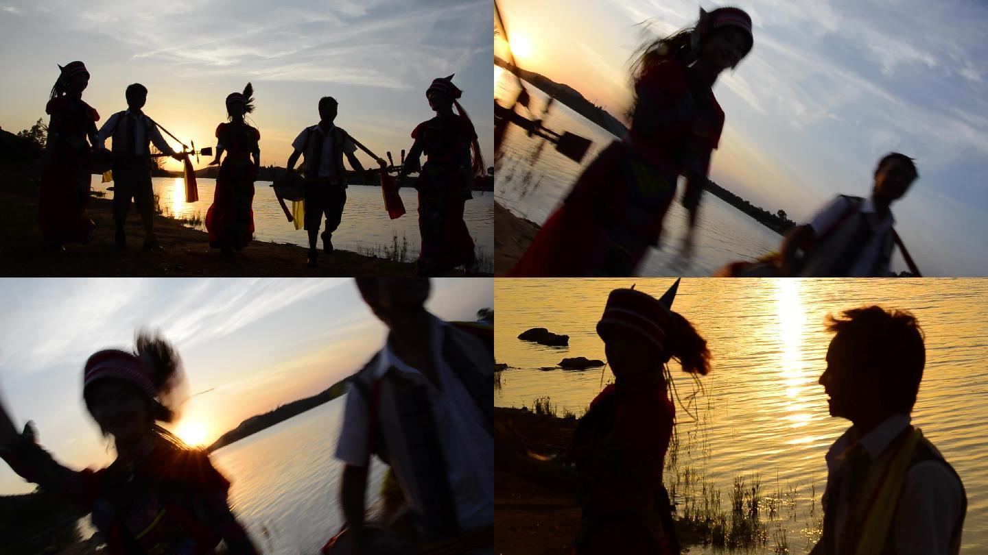 夕阳下湖水边少数民族舞蹈剪影