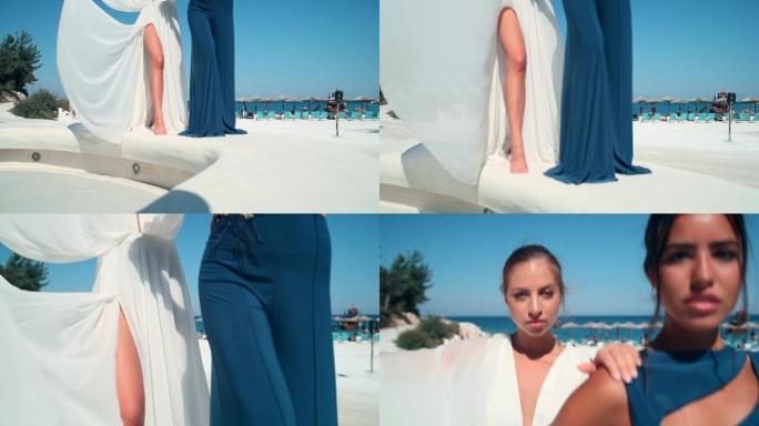 美丽的年轻时装模特在海滩边穿着飘逸设计师的夏装摆姿势