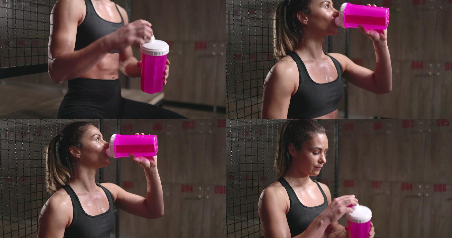 汗流浃背的女运动员在更衣室喝水。