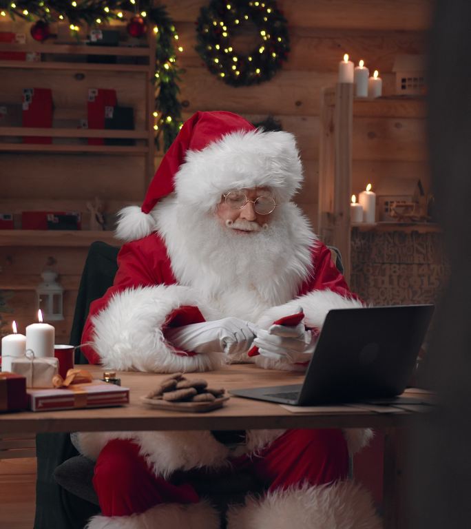 圣诞老人正在他的红色智能手机上拨打一些号码
