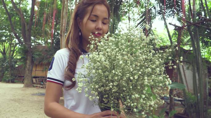 手持白花的亚洲女子站在大自然中