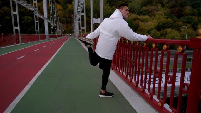 早上在基辅跑步前在桥上伸展身体的男子