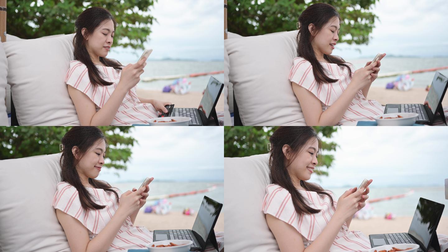 亚洲女商人在度假海滩椅上使用在线智能手机和笔记本电脑检查股票价格并投资股市和加密货币