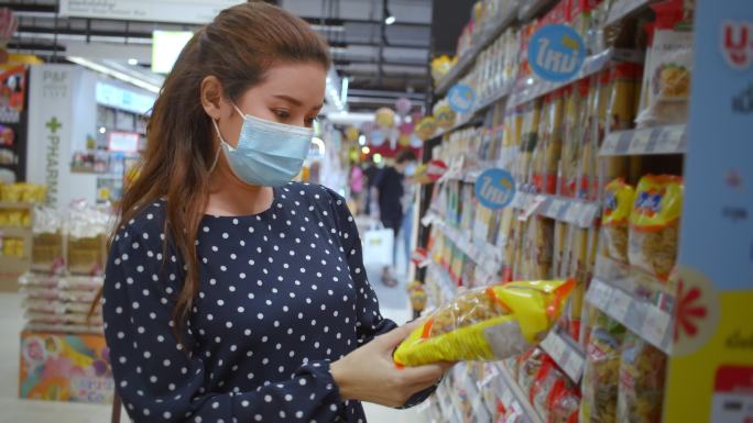 美丽的女人在超市购物阅读和挑选食物