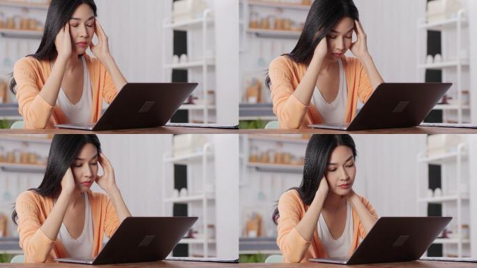 亚洲女商人在家工作太累了，她在笔记本电脑前压力很大。