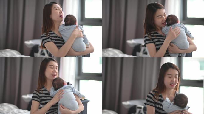 亚裔中国年轻母亲在卧室抱着她的男婴