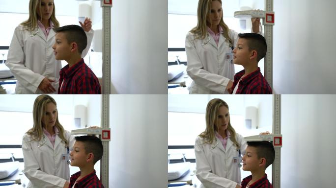 友好的儿科医生在会诊时测量兴奋的小男孩的身高