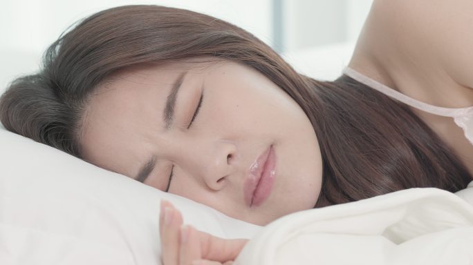 睡在床上的女人晚上被智能手机的来电吵醒。