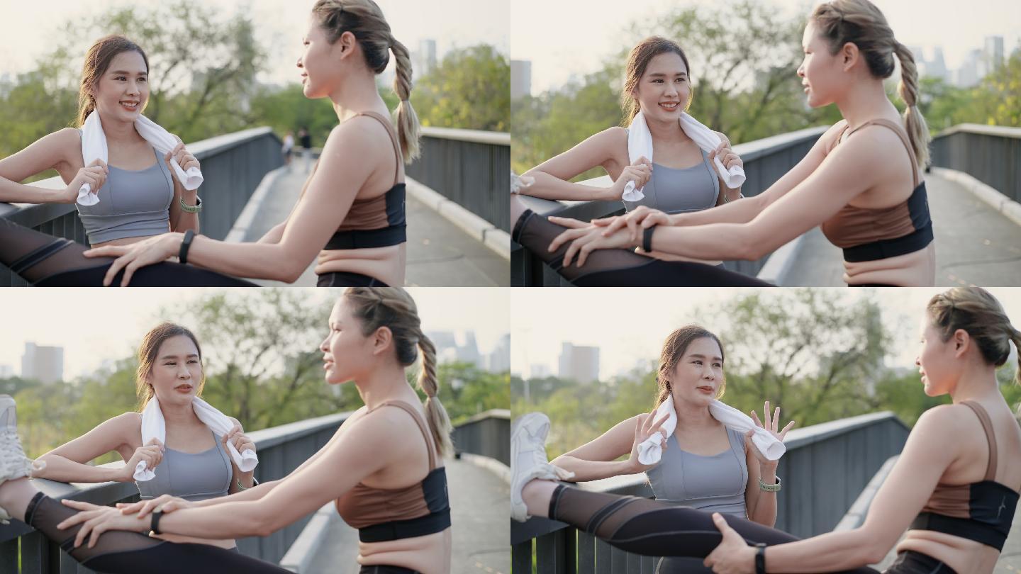 两位穿着运动装的亚洲美丽中年女性朋友在一起聊天，其中一位伸展双腿，另一位则在一起锻炼后擦汗，这是在市