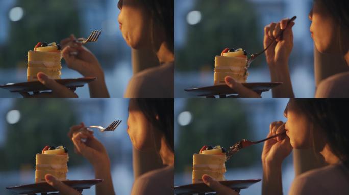 日落时分，中国亚裔美女在家吃蛋糕，透过窗帘远眺