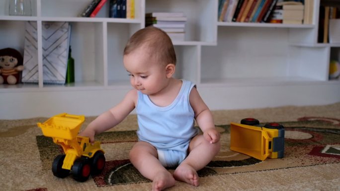 婴儿在房间里玩耍坐在地毯上的小孩儿工程车