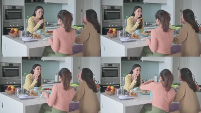 3位亚裔中国女性朋友周末在厨房柜台在家享用早餐