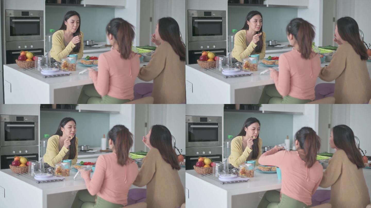 3位亚裔中国女性朋友周末在厨房柜台在家享用早餐