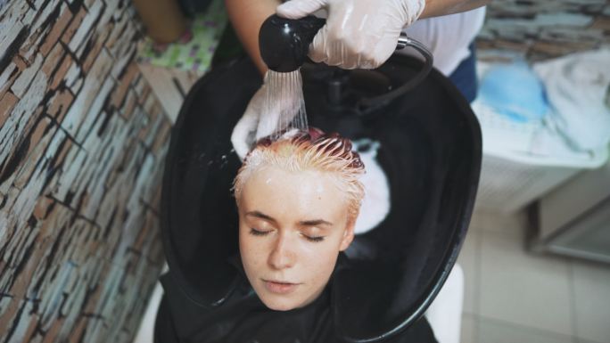 一位年轻女子在美发沙龙染发和洗发的高角度照片