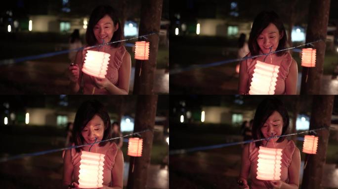 亚洲华人妇女在纸灯笼上点燃蜡烛，庆祝中秋节。