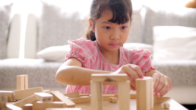 小女孩在家的起居室里搭建木块