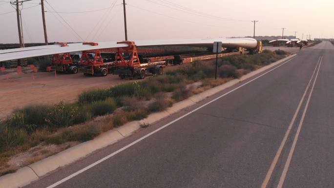 风力涡轮机由超长平板半挂卡车从墨西哥运过边境，并排停放