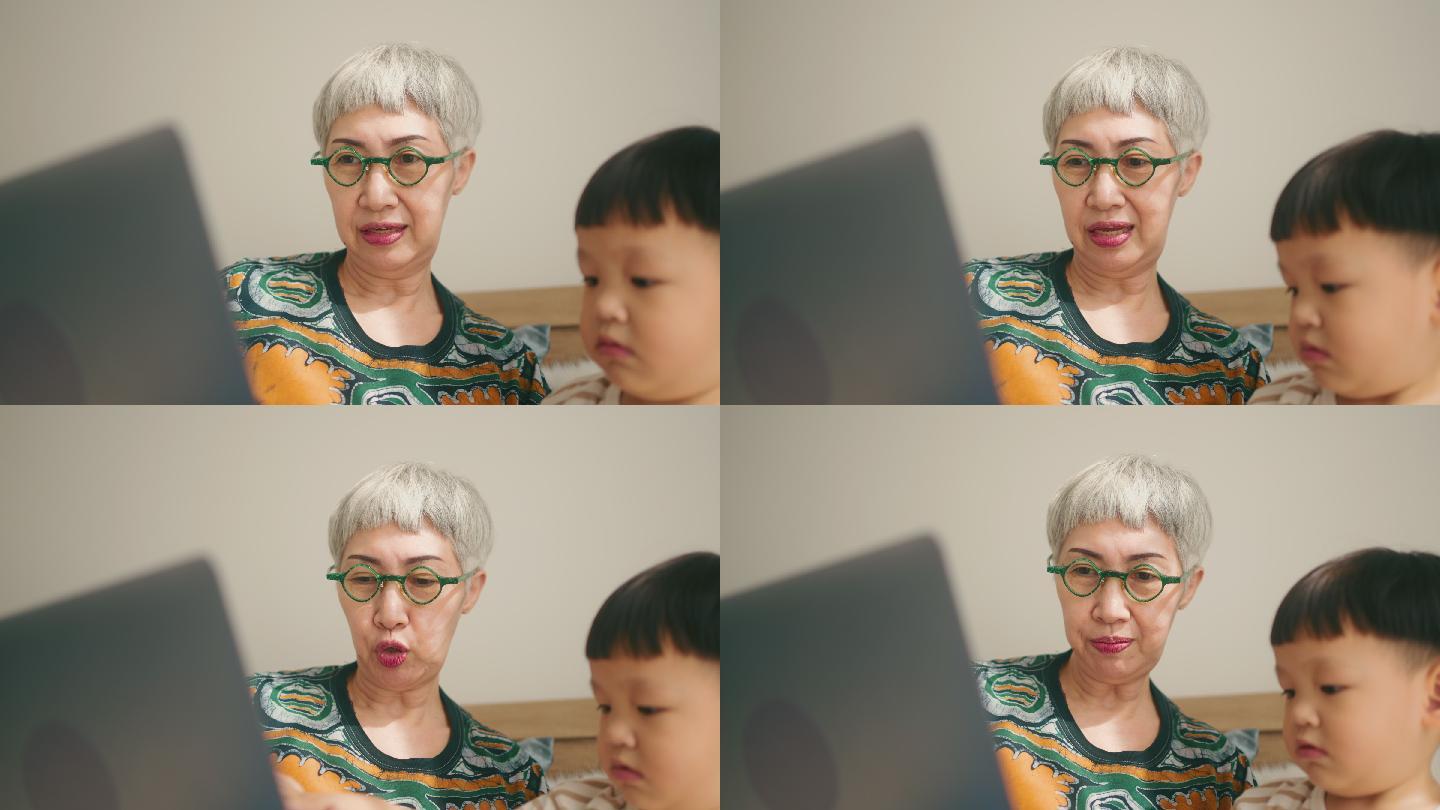 漂亮的祖母带着孩子在家里使用笔记本电脑