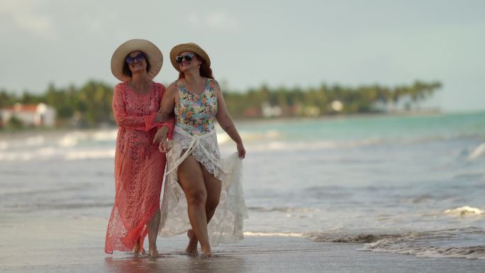 母亲和女儿手拉手在海滩上散步