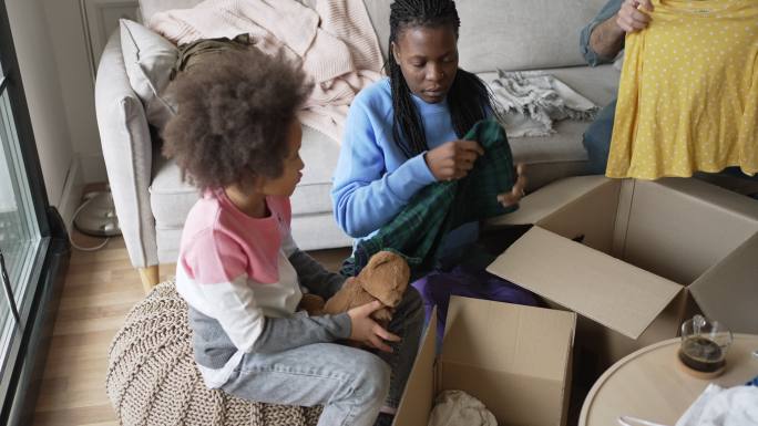 多种族家庭在捐款箱中折叠和整理衣服。