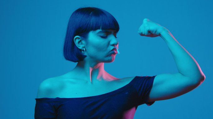 年轻女性柔韧的二头肌独立于蓝色霓虹灯的广告空间