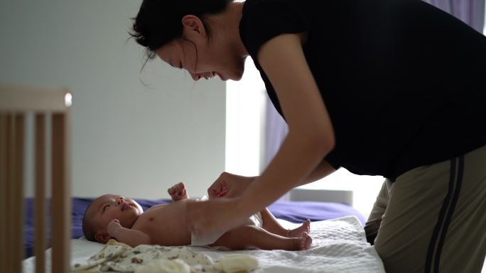 亚洲母亲在床上为婴儿换尿布