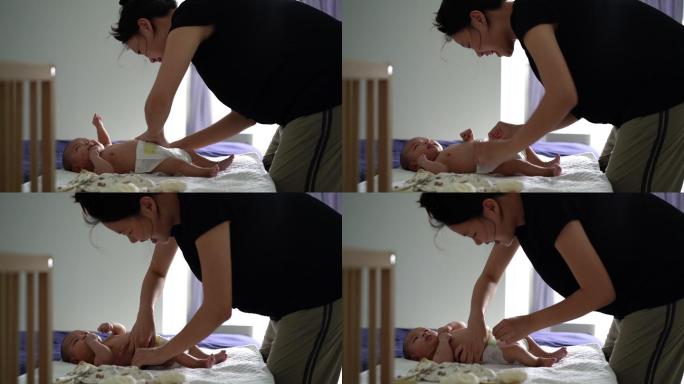 亚洲母亲在床上为婴儿换尿布