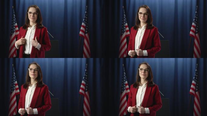身穿红色夹克的年轻女政治家站在蓝色背景下，愉快地微笑着在镜头前摆姿势