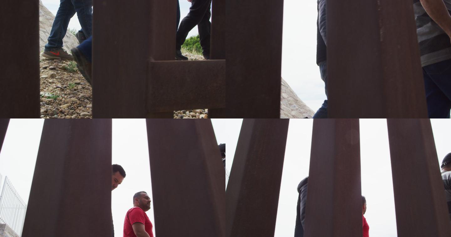 阳光明媚的日子里，五名西班牙裔男子和一条狗在美墨边境的钢条墙墨西哥一侧与一条狗散步的慢镜头，相机在美