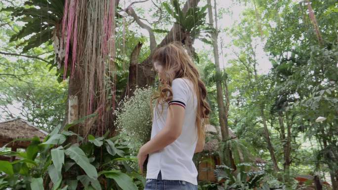 稳定镜头：亚洲女子手持白花站在大自然中