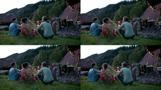 日落时分，三个朋友在山间小屋外休息