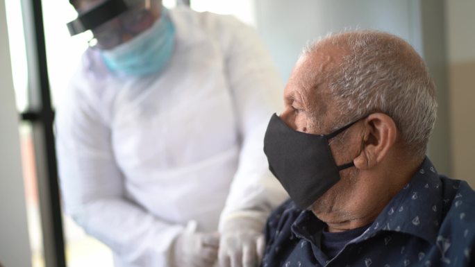 女医生为戴口罩的老人接种疫苗