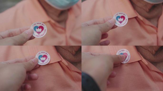 ECU PoV女性手将接种疫苗的贴纸贴在男性老年人的衬衫上