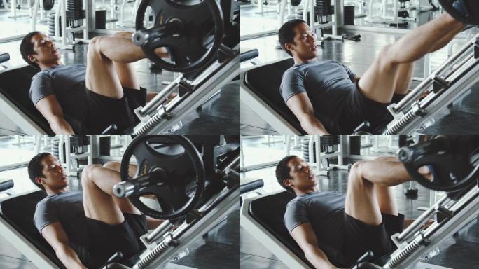 帅哥在健身房的机器上锻炼双腿