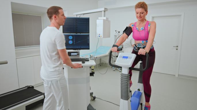 LD医生监督一名中年女性在自行车上进行的心脏压力测试