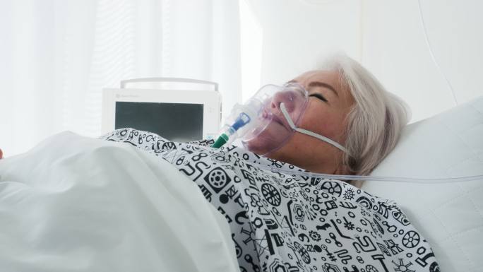 病房：美丽的老妇人戴着氧气面罩躺在床上，病后完全康复。老太太梦想着她的家人、朋友、幸福的生活。