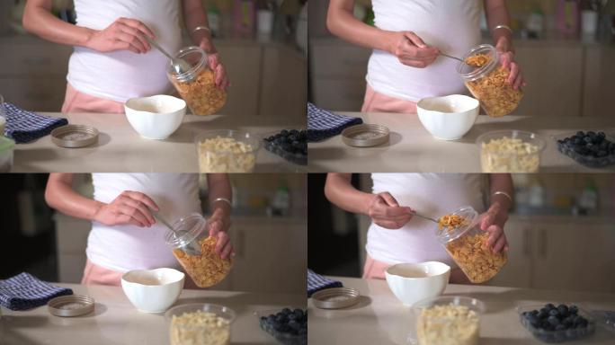 孕妇在家里做早餐玉米片，在厨房里添加配料。制作富含纤维和营养的健康有机膳食