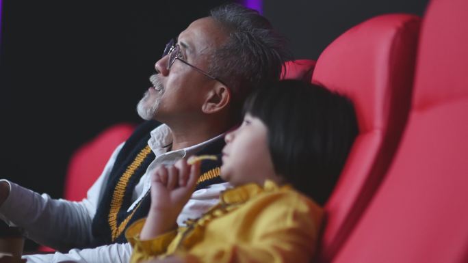 侧视亚裔华人活跃老人和孙女在电影院看电影