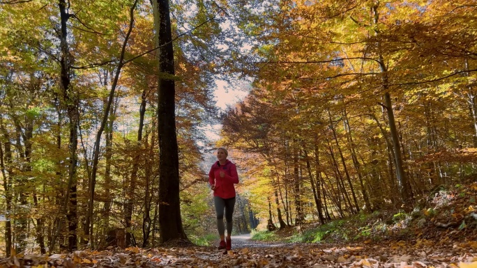 秋天阳光明媚的一天，TS女跑步者在森林中跑步