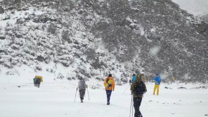 四川阿坝松潘风雪中穿越山谷的徒步旅行者