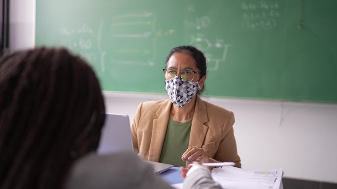 老师在教室里与学生交谈-戴口罩