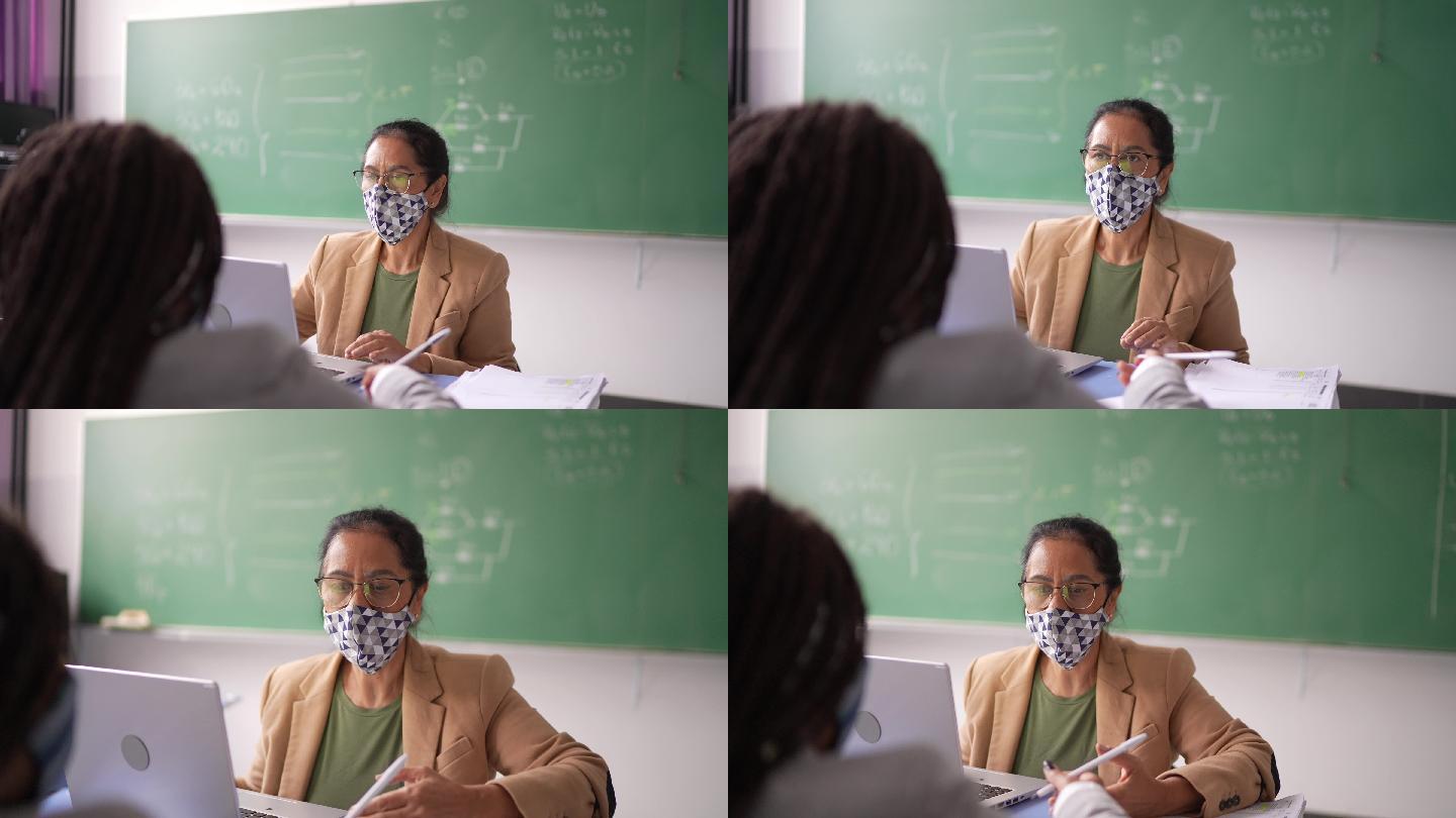 老师在教室里与学生交谈-戴口罩