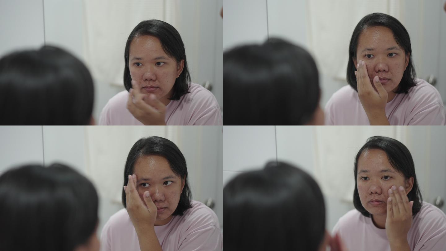 亚洲女性在镜子里看自己的脸涂面霜